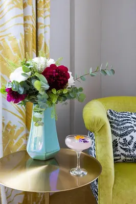a vase with flowers on a table next to a chair at Maalot Roma - Small Luxury Hotels of the World in Rome