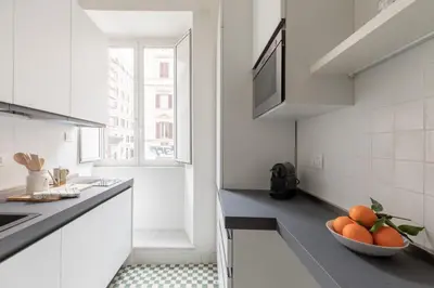 a white kitchen with a bowl of oranges on the counter at iFlat Lovely Apartment for Groups in Rome