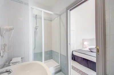 a bathroom with a shower and a sink and a bed at Biancorè in Rome