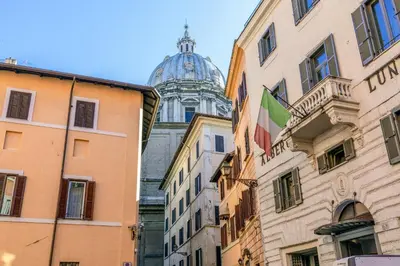 a view of a cathedral from between buildings at Rome As You Feel - Paradiso Apartment in Rome
