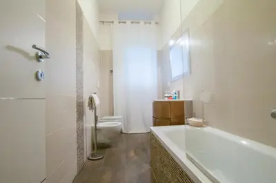 a white bathroom with a tub and a toilet at Demi's home in Rome