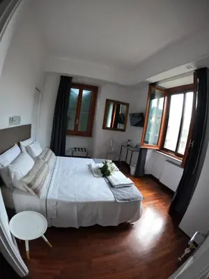 a bedroom with a bed and a table and windows at EMI's Guest House in Rome