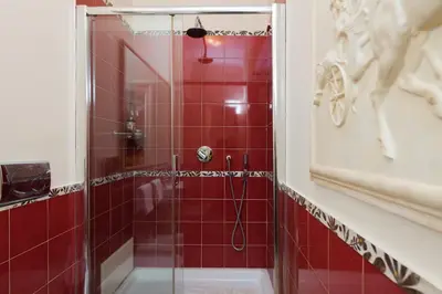 a red tiled shower with a glass door in a bathroom at Luxury Apt with Colosseum View in Rome