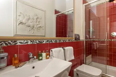 a bathroom with a sink and a toilet and red tiles at Luxury Apt with Colosseum View in Rome