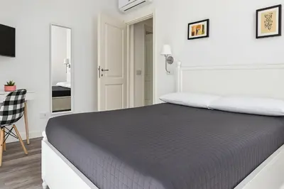 a white bedroom with a bed and a desk at Casa Giustiniano - Metro San Paolo in Rome