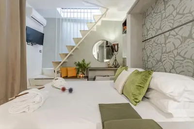 a bedroom with a large white bed and a staircase at Green Terrace Loft Colosseum in Rome