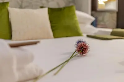 a flower sitting on top of a white bed at Green Terrace Loft Colosseum in Rome