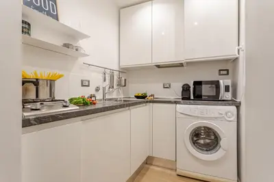 a kitchen with white cabinets and a washer and dryer at Green Terrace Loft Colosseum in Rome