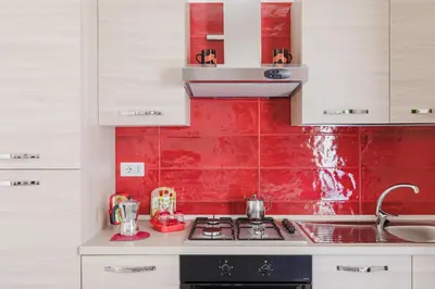 a kitchen with white cabinets and a red wall at My Home in San Pietro in Rome
