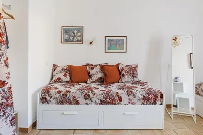 a white bedroom with a bed with a floral bedspread at My Home in San Pietro in Rome