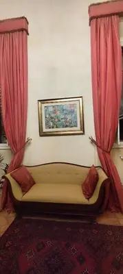 a couch sitting in a room with pink curtains at Residenza al Pantheon - RH Collection in Rome