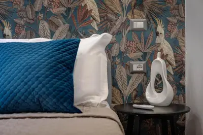 a bedroom with a bed with a blue pillow and a side table at The Venue Sistina in Rome