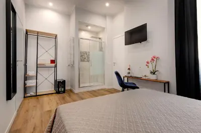 a bedroom with a bed and a desk and a television at The Venue Sistina in Rome