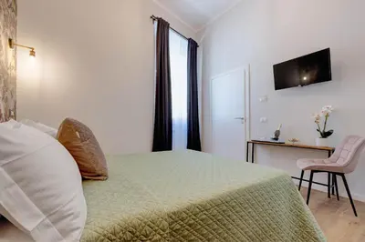 a bedroom with a bed and a table and a chair at The Venue Sistina in Rome