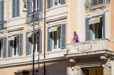 a woman standing on a balcony of a building at Hotel La Place Roma in Rome