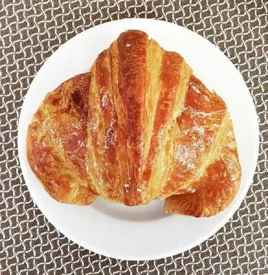 a white plate with two croissants on a table at Hotel La Place Roma in Rome