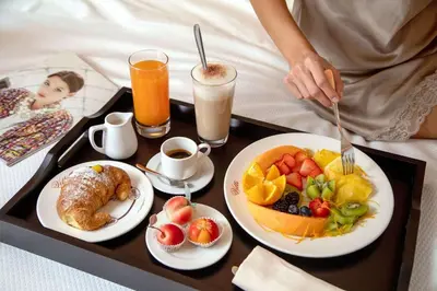 a tray of breakfast foods on a bed with a woman at Hotel La Place Roma in Rome