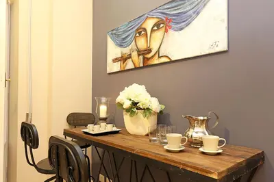 a table with a vase of flowers and a painting at Daplace - Lucrezia Apartment in Rome