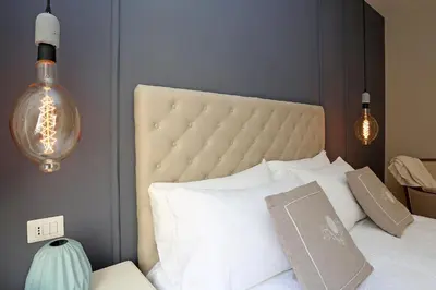 a bedroom with a white bed with two lights at Daplace - Lucrezia Apartment in Rome