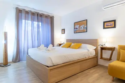 a bedroom with a large bed and a yellow chair at Domus Domi Barberini Sq. in Rome