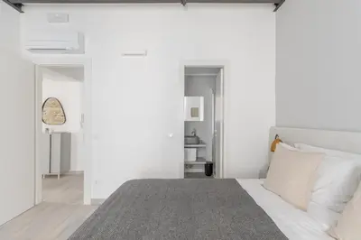 a bedroom with white walls and a bed with a gray rug at Saint Peter Elegant and Charming Apartment in Rome