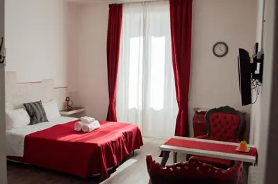 a bedroom with red curtains and a bed and a chair at Relais Cola Di Rienzo in Rome
