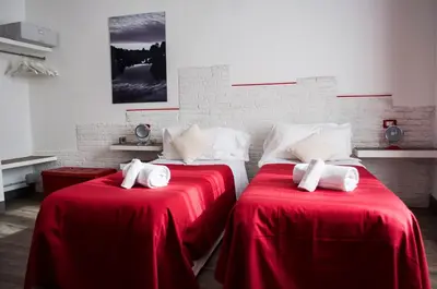 two beds in a room with red sheets at Relais Cola Di Rienzo in Rome