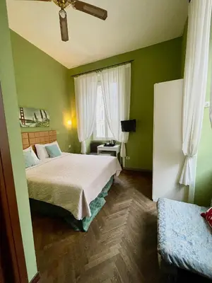 a green bedroom with a bed and a window at Guest House Meret in Rome