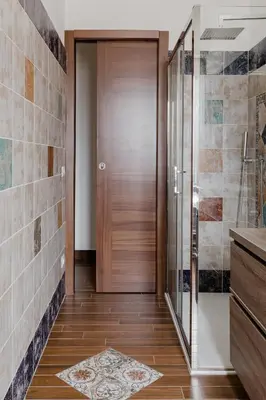 a wooden door in a bathroom with a tile wall at Scarfoglio Apartment, 4 persone, 2 camere, balcone, Wi-Fi, Stazione Tiburtina in Rome