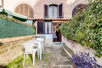 a patio with two chairs and a table in front of a building at Charming Apartment with Garden, Parking & Metro in Rome