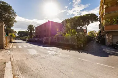 an empty street with a red building and trees at Charming Apartment with Garden, Parking & Metro in Rome