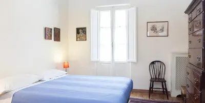 a bedroom with a bed and a chair and a window at Libri Flat in Rome