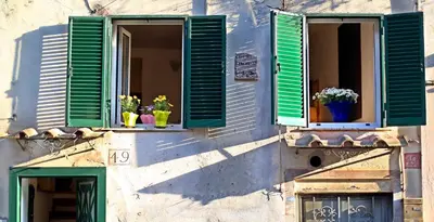 two windows with green shutters with potted plants on them at Lovely Maisonette Trastevere in Rome
