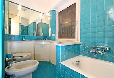 a blue tiled bathroom with a sink and a toilet at Lovely Maisonette Trastevere in Rome