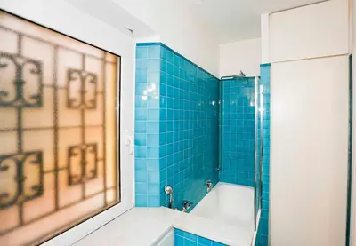 a blue tiled bathroom with a tub and a shower at Lovely Maisonette Trastevere in Rome