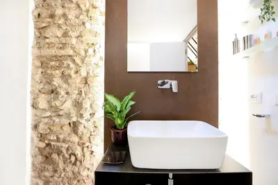 a bathroom with a white sink and a stone wall at Sky Dream Loft Trastevere in Rome
