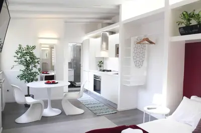 a white kitchen with a white table and a table and chairs at Bright Cozy Studio Trastevere in Rome