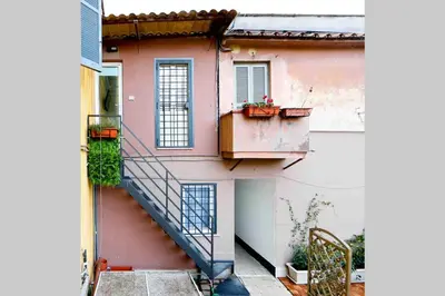 a stairway leading up to a pink building with a balcony at Bright Cozy Studio Trastevere in Rome