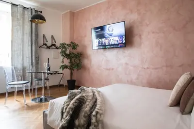 a living room with a bed and a tv on a wall at Pink Intimate Jacuzzi Suite Trastevere in Rome