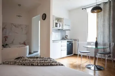 a bedroom with a bed and a table and a kitchen at Pink Intimate Jacuzzi Suite Trastevere in Rome