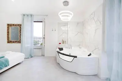 a white bathroom with a tub and a bed at White Panoramic Jacuzzi Suite Trastevere in Rome