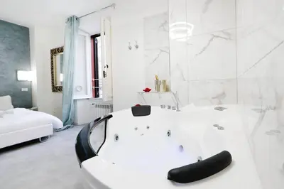 a white bathroom with a white tub and a bed at White Panoramic Jacuzzi Suite Trastevere in Rome
