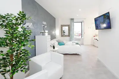 a white living room with a white couch and a plant at White Panoramic Jacuzzi Suite Trastevere in Rome