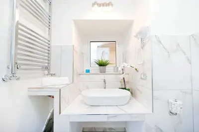 a white bathroom with a sink and a mirror at White Panoramic Jacuzzi Suite Trastevere in Rome