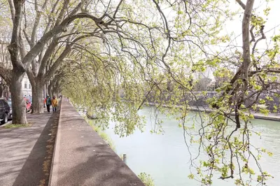people walking along a sidewalk next to a river at Campo dè Fiori Detached Apartment Eligio - Top Collection in Rome