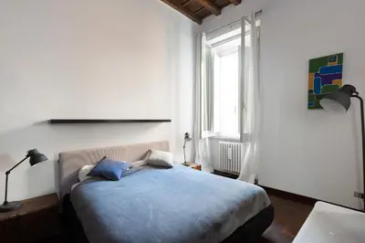 a bedroom with a bed with blue sheets and a window at Rufina Apartment in Rome