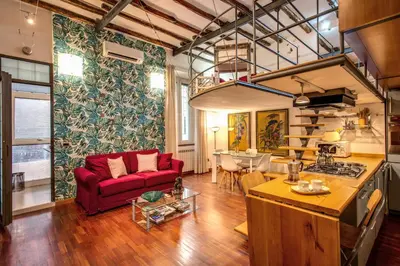 a living room with a red couch and a kitchen at San Calisto Suite in Rome