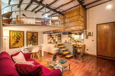 a living room with a red couch and a kitchen at San Calisto Suite in Rome