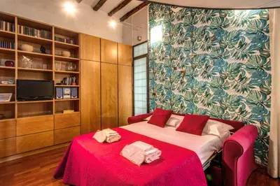 a bedroom with a bed with a red blanket and towels at San Calisto Suite in Rome