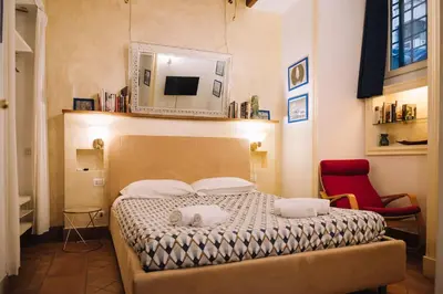 a bedroom with a bed with a mirror and a red chair at Limani - Navona Private Apartment in Rome